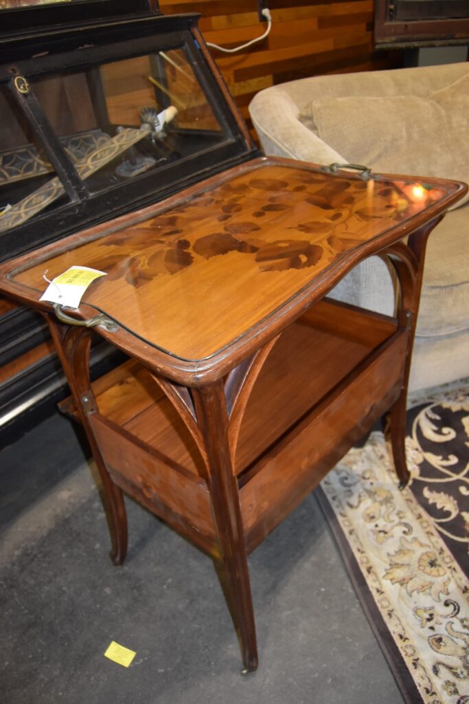 Vintage art nouveau marquetry serving cart with leaf inlay under glass, featuring antique hardware and a magazine shelf. A unique secondhand furniture find at our Baltimore non-profit.